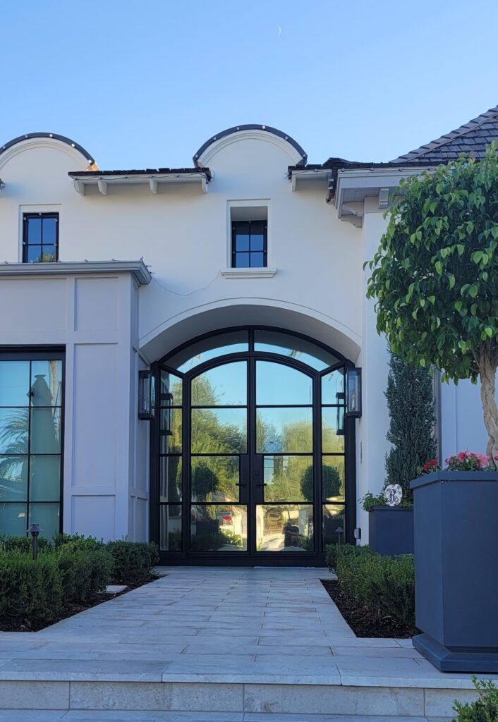 Luxury home entry with tall arched black-framed glass doors
